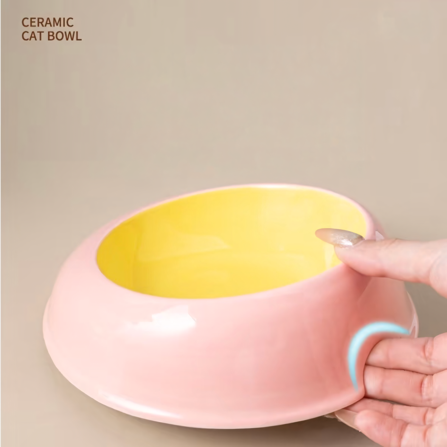 A hand easily picking up the heavy ceramic cat bowl from a flat surface using the cleverly designed hidden ergonomic lift notch at the base.