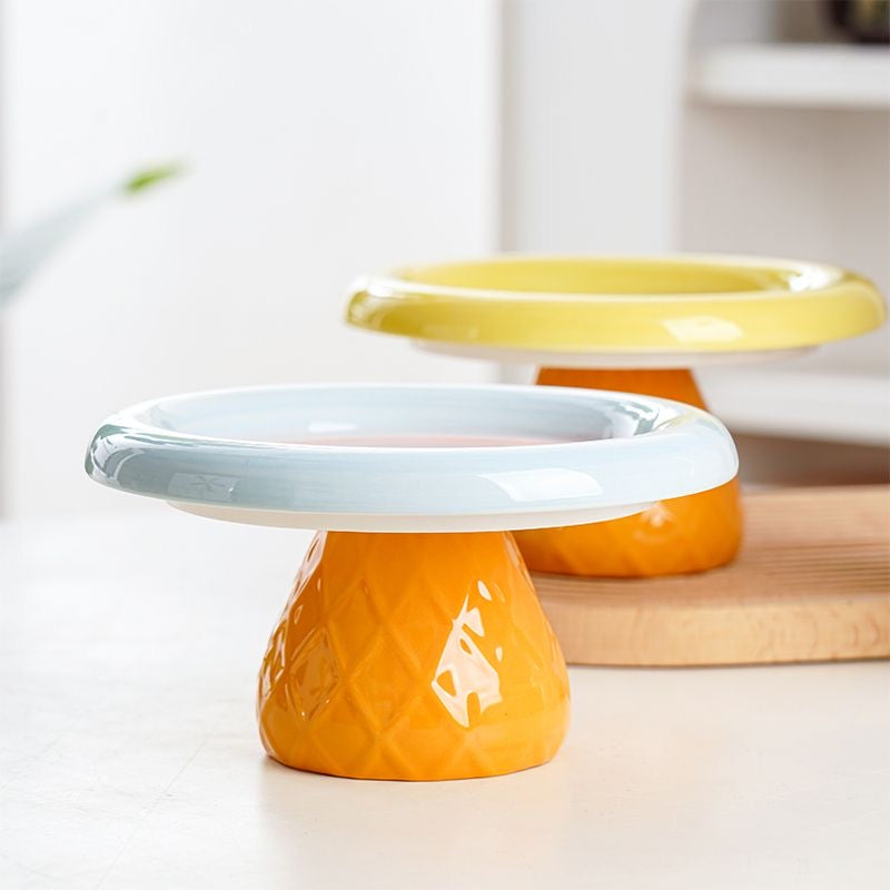 Side profile of the pastel blue and yellow elevated ceramic cat bowls on their textured orange pedestal bases. Designed with a 9.8cm optimal height for healthy eating posture.