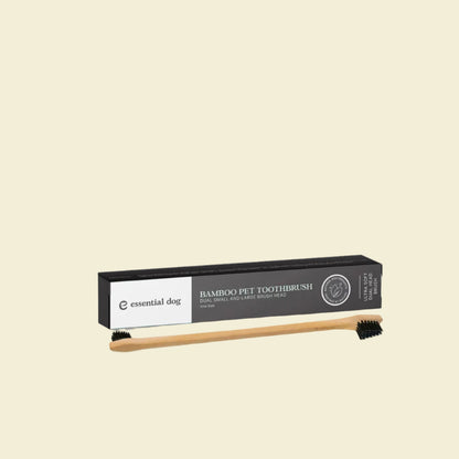 The Essential Dog double-sided bamboo pet toothbrush displayed in front of its sleek black packaging box, highlighting the ultra-soft dual small and large brush heads.