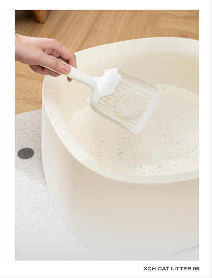A hand using a white scoop to effortlessly lift a firm, round clump of Xu Cuihua natural cassava cat litter from a white litter box, showcasing its rapid clumping performance and fine, paw-friendly texture with visible blue silver ion granules.