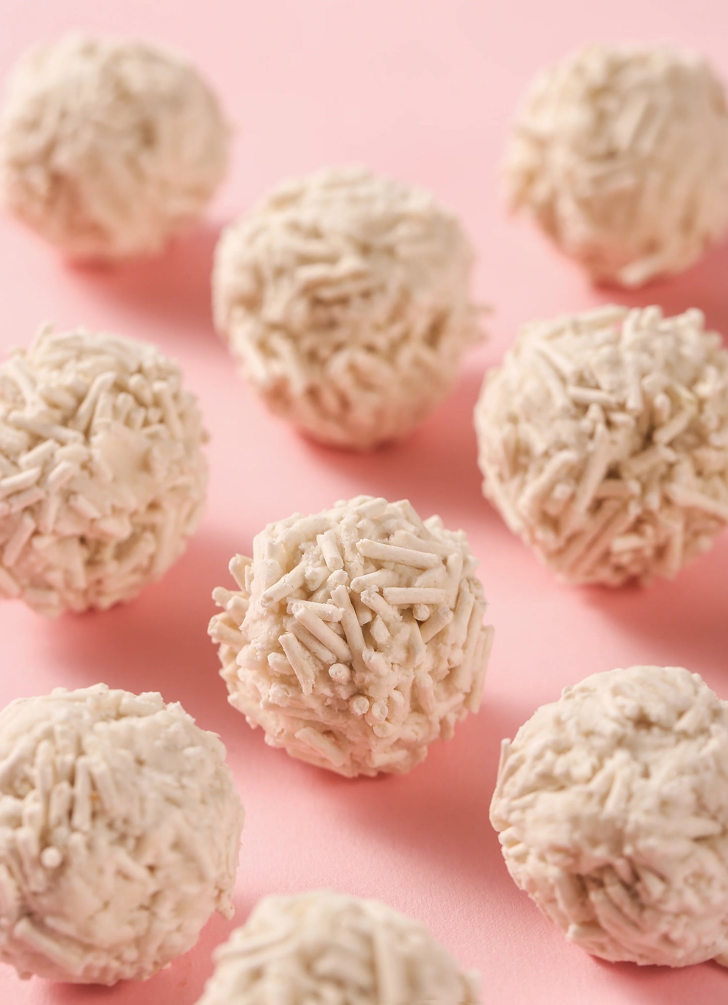Firm, solid round clumps formed by the Twinkle Tale tofu cat litter displayed on a pink background, showcasing its fast-clumping and easy-scooping capabilities without crumbling.