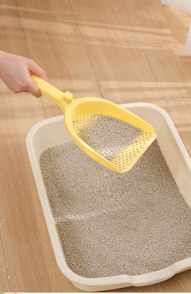 A person using the yellow oversized cat litter scoop to effortlessly sift clean mineral litter, leaving solid waste behind in the litter box.