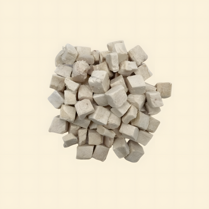 A pile of single-ingredient freeze-dried chicken cubes on a white background, highlighting a clean and lean high-protein training treat for pets.