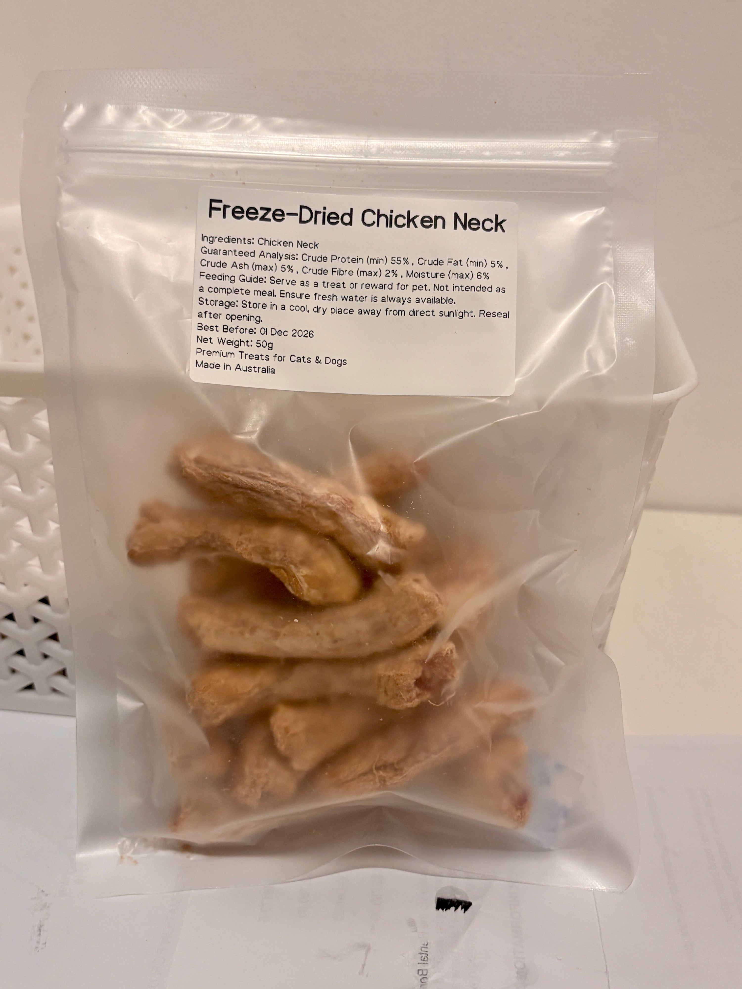 A clear and resealable 50g bag of Freeze-Dried Chicken Neck treats, featuring a printed label that details the 100 percent single-ingredient formula, feeding guide, and Australian Made quality.