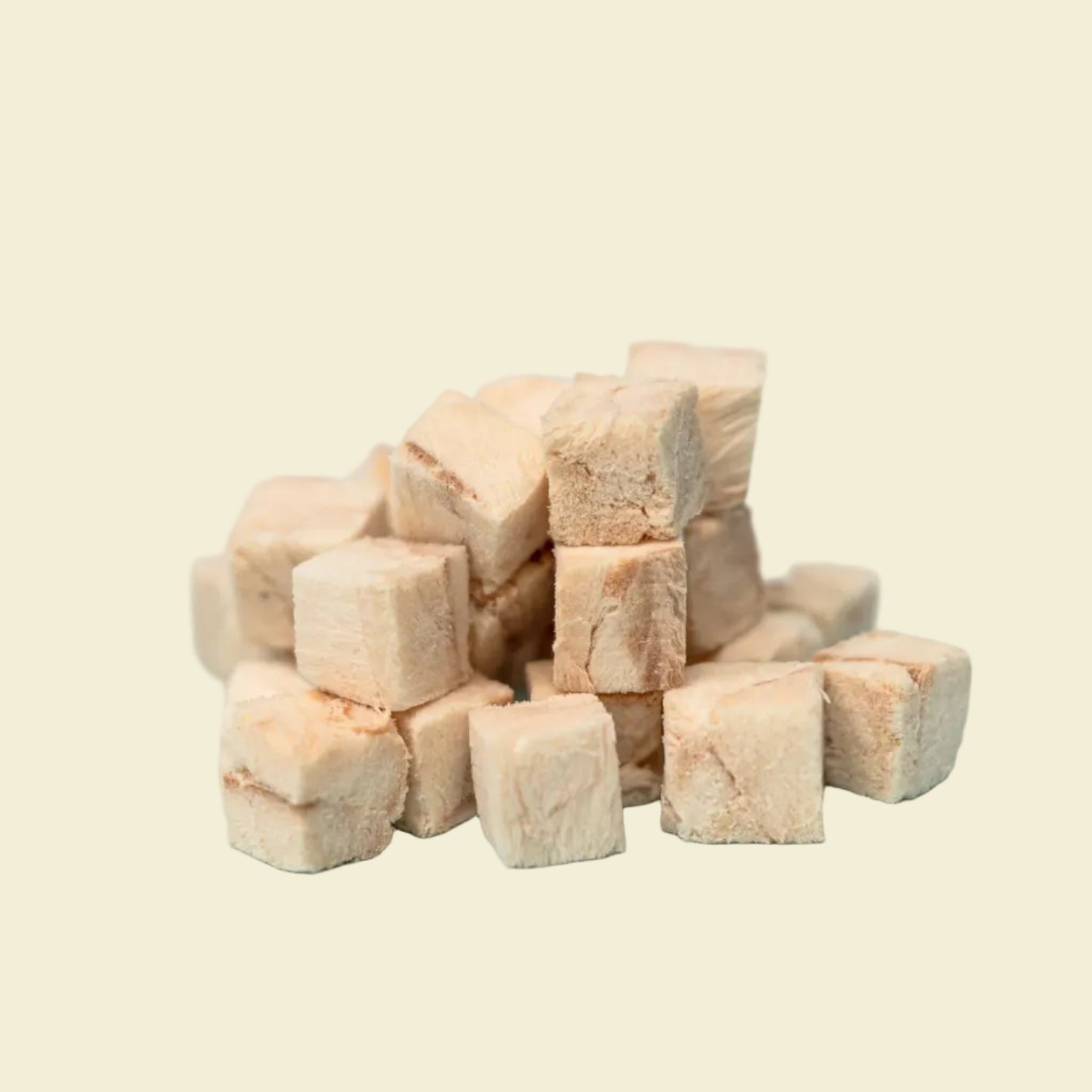 A close-up view of premium freeze-dried cod cubes piled on a light blue background, highlighting the single-ingredient, ultra-high protein ocean treat for pets.