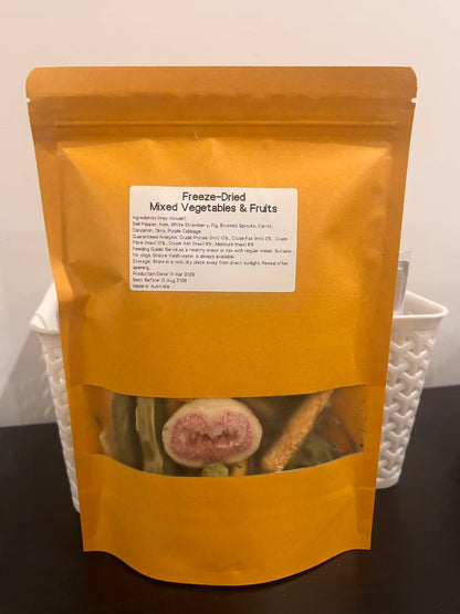 A real-world photo of the Freeze-Dried Mixed Vegetables &amp; Fruits dog treat in a premium kraft pouch. The label displays the Australian-made origin and ingredients, with a clear window showing a freeze-dried fig slice and healthy green veggies.