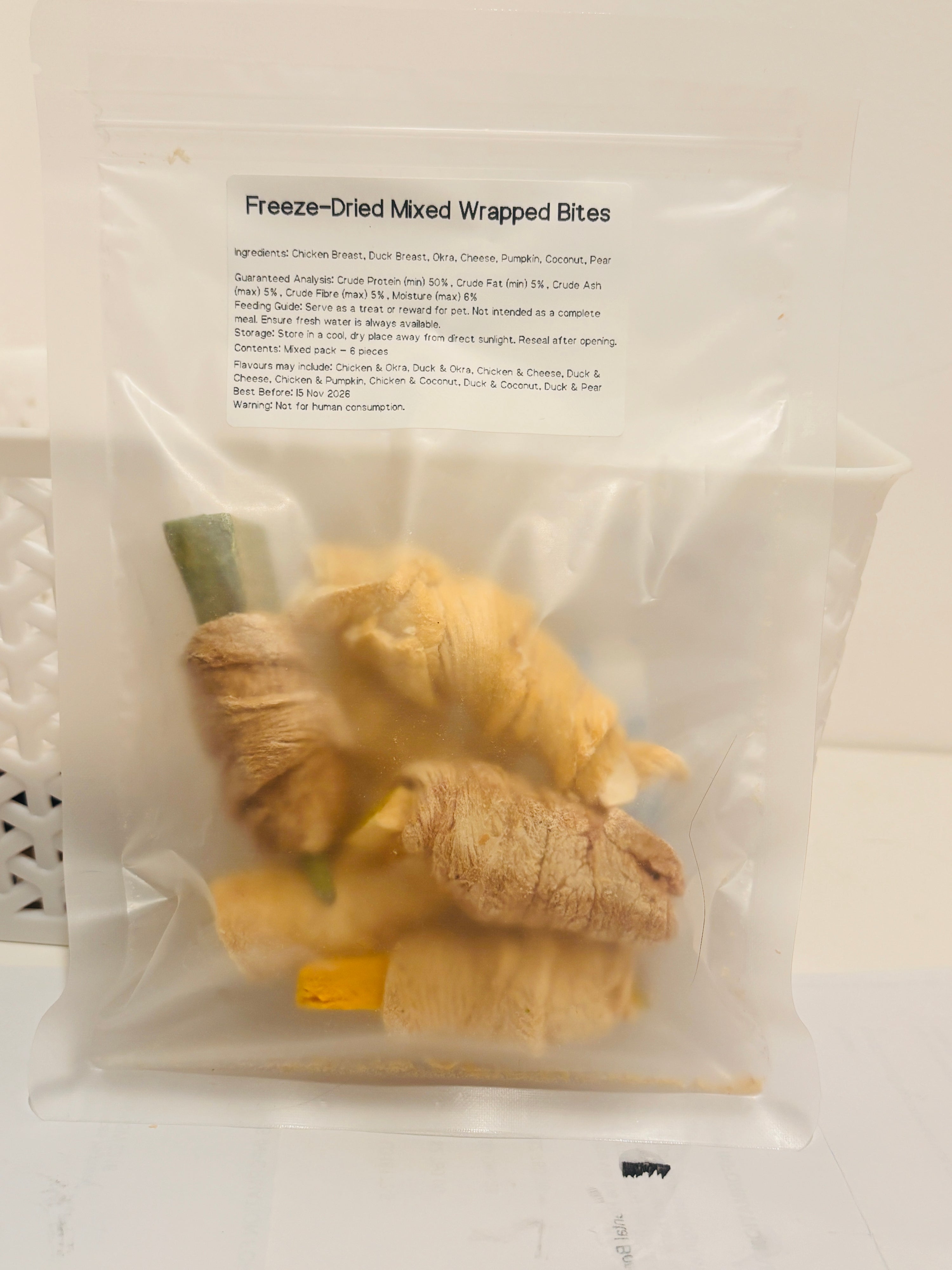 A clear, resealable bag containing a 6-piece mixed pack of Freeze-Dried Wrapped Bites, featuring a printed label that details the meat and superfood ingredients, feeding guide, and a minimum of 50 percent crude protein.