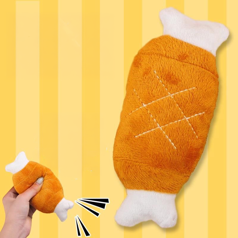 Close-up of the Plush Giant Chicken Leg toy on a yellow striped background, with an inset showing a hand squeezing the toy to trigger the internal squeaker.