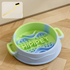 A green and blue pastel swirl silicone slow feeder bowl placed on a wooden floor, featuring an inset graphic of the complimentary cleaning brush designed for effortless maintenance.