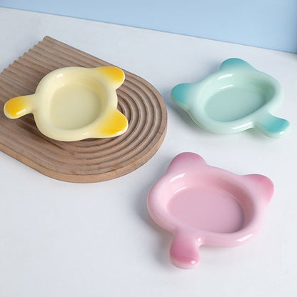 Three glossy Chubby Cat ceramic feeding plates in pastel yellow, mint blue, and pink. The ultra-smooth glaze prevents sticky food residue and feline chin acne.