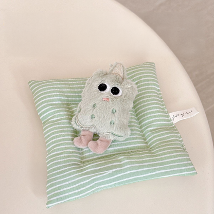 A close-up view of the kawaii green matcha biscuit plush squeaky toy, showcasing its soft texture, embroidered smiling face, and tiny decorative party hat.