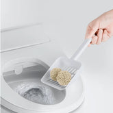A hand scooping Kungfu Cat tofu litter clumps directly into a toilet, illustrating that the litter is completely water-soluble and flushable.