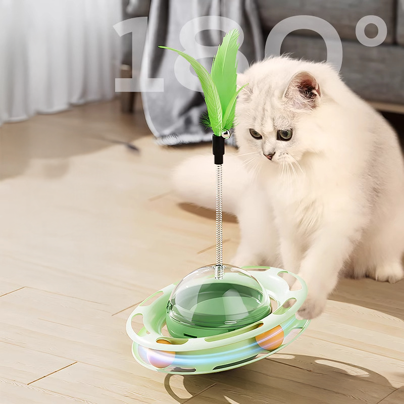 White cat batting at the Green Boredom Buster toy. Features a self-balancing tumbler design and spinning track balls for cognitive enrichment