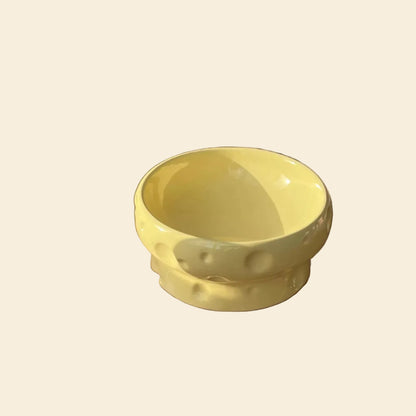 Cheese Ceramic Pet Bowl in buttery yellow with playful cheese hole indentations. The wide, shallow basin offers whisker stress relief and is made of acne-free non-porous ceramic