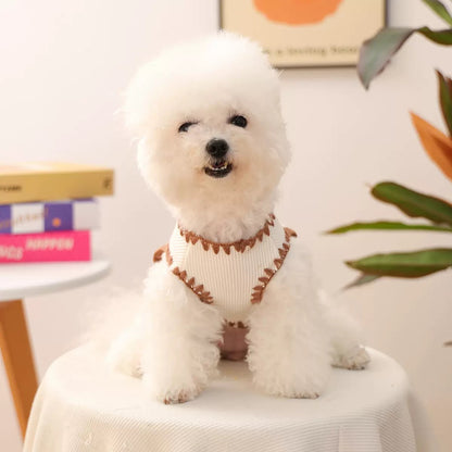 Front view of the vest on a fluffy dog showing the sensory-soft ribbed trim. The cream-colored edging prevents chafing on sensitive skin