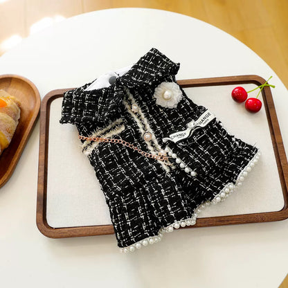 tyled flat lay of the Luxury Tweed Dog Dress with a cherry. Detailed view of the woven tweed texture and &