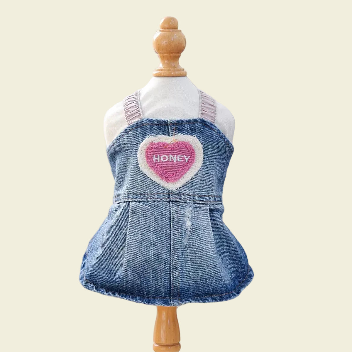 Front view of the Honey Heart Denim Dress on a mannequin. Highlights the elastic ruffled shoulder straps and the vintage-style pink heart appliqué