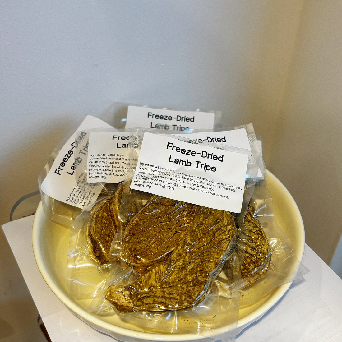 Multiple pouches of Freeze-Dried Lamb Tripe on a plate, a natural probiotic supplement to soothe sensitive dog stomachs.