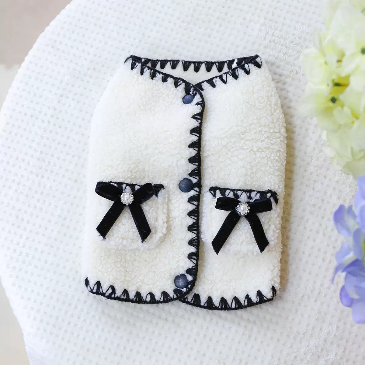 Flat lay of the white Sherpa pet vest. Features smooth snap buttons along the front for a quick, frustration-free dressing experience without snagging fur