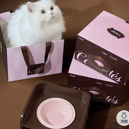 White fluffy cat sitting inside the pink gift bag next to the stacked Mango Cannelés Patisserie boxes and the cocoa-colored elevated ceramic bowl