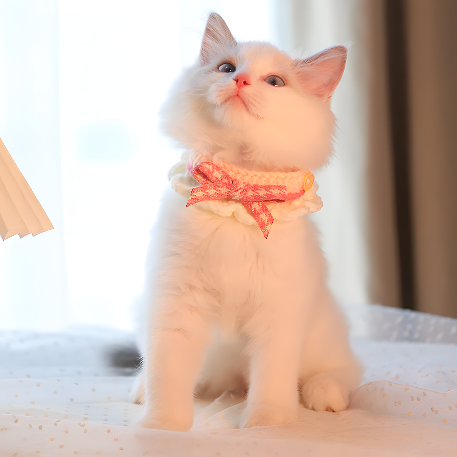 White cat looking up while wearing the pink houndstooth bib. The lightweight design sits gently on the chest without restricting movement