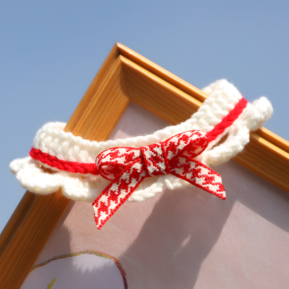 Hand-knitted pet bib featuring a classic red houndstooth bow tie. A preppy-chic accessory made from soft milk cotton for sensitive skin