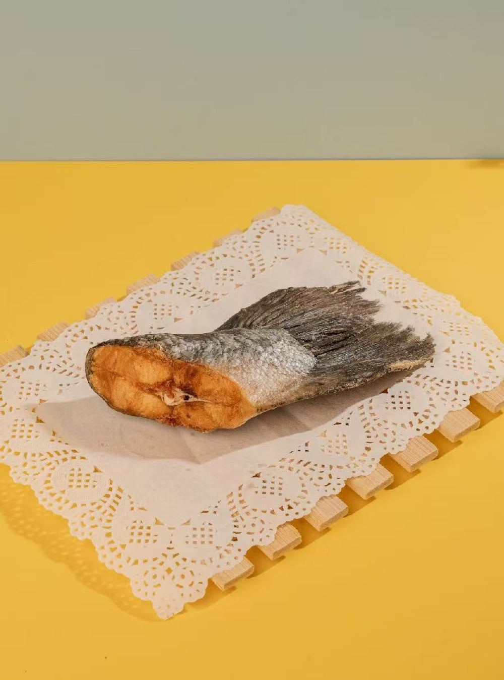 A salmon tail chews on the table, perfect as a crunchy ASMR treat and natural beauty supplement for dogs.