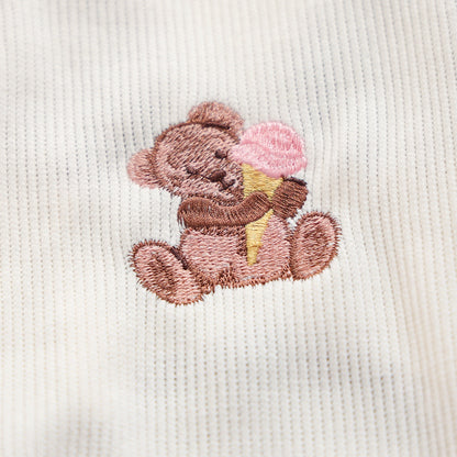 Macro shot of the tiny bear holding a pink ice cream cone embroidery. High-quality stitching that adds a dopamine design element to the white vest