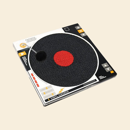 Angled view of the record-shaped cat scratch pad. Features a spring-loaded pom-pom ball that mimics prey to keep cats engaged and active
