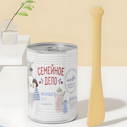 A butter yellow silicone spatula standing vertically next to a large, deep pet food can. The long ergonomic handle is perfect for reaching the bottom of dog and cat food tins.