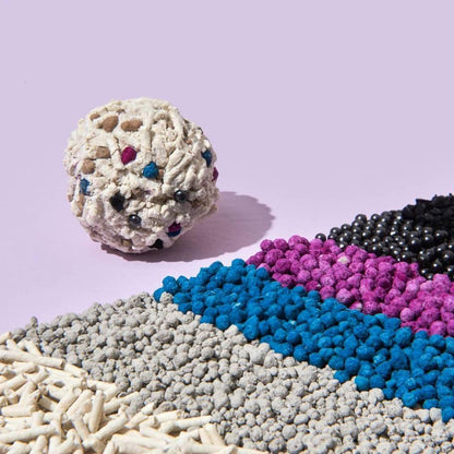A solid clump of Michu cat litter displayed next to its raw ingredients in neat rows, including natural tofu, bentonite, blue and pink odor-neutralizing particles, and activated carbon beads.