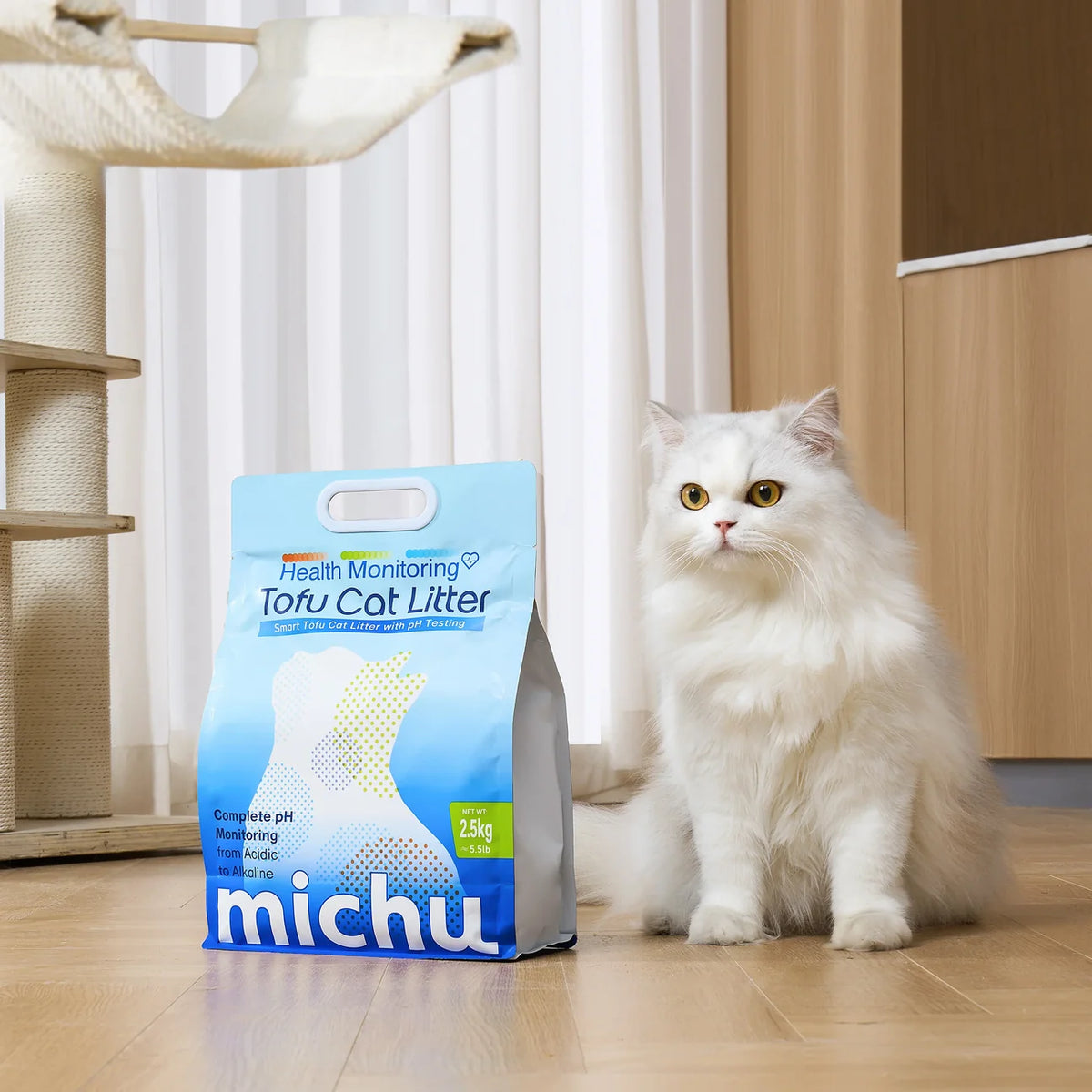 White Persian cat sitting beside a package of Michu health monitoring tofu cat litter on a wooden floor in a home interior.