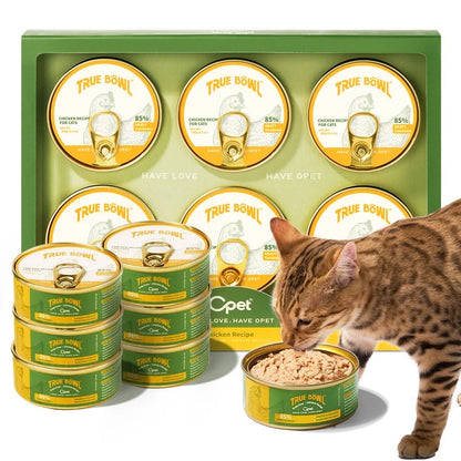 Cat eating Chicken Recipe pâté beside an OPET TRUE BÖWL multipack and several cans
