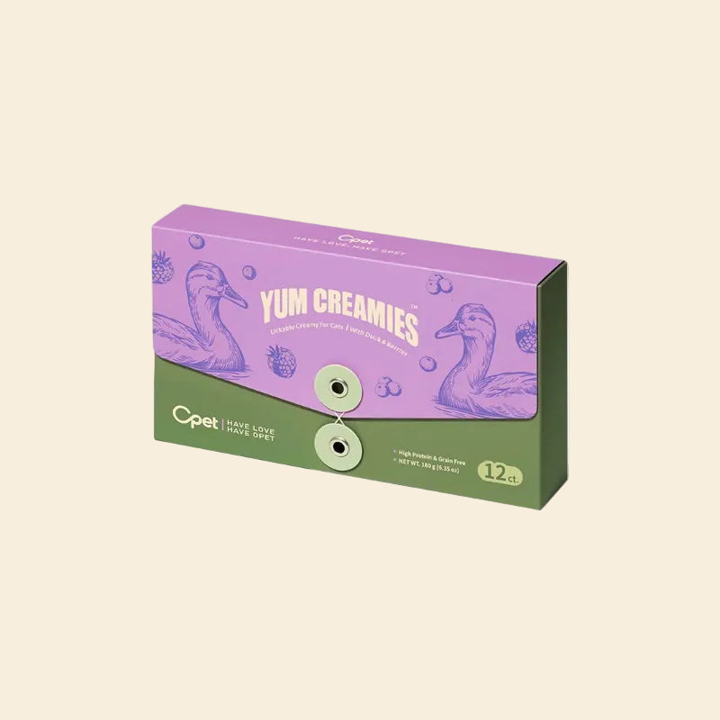 A purple and green 12-pack box of OPET Yum Creamies lickable cat treats in Duck &amp; Berries flavor, featuring a vintage illustration of a duck and fresh berries.