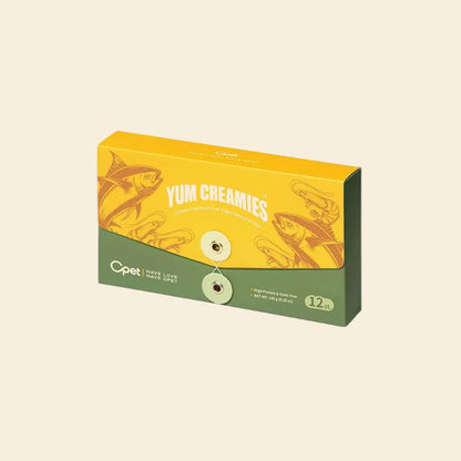 A yellow and green 12-pack box of OPET Yum Creamies lickable cat treats in Tuna &amp; Shrimp flavor, featuring vintage illustrations of a tuna fish and shrimp.