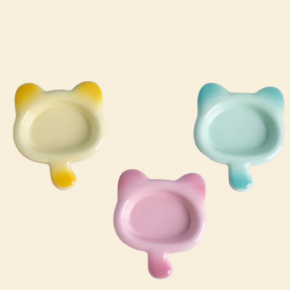 Top-down view of three Chubby Cat Ceramic Pet Plates in yellow, mint blue, and pink gradient colors.