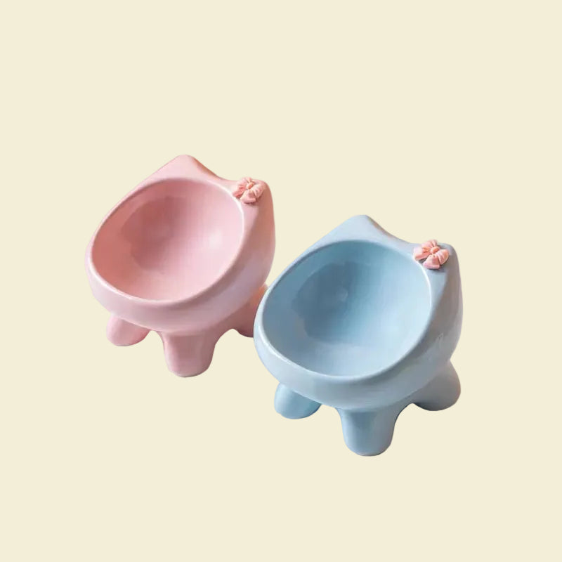 Two elevated ceramic cat bowls in pastel pink and light blue, angled to show the deep, smooth curved interior that naturally gathers kibble.