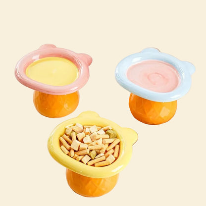 A vibrant collection of three pastel Teddy Bear elevated pet bowls in pink, blue, and yellow colorways. The yellow bowl is filled with dry kibble and freeze-dried treats.