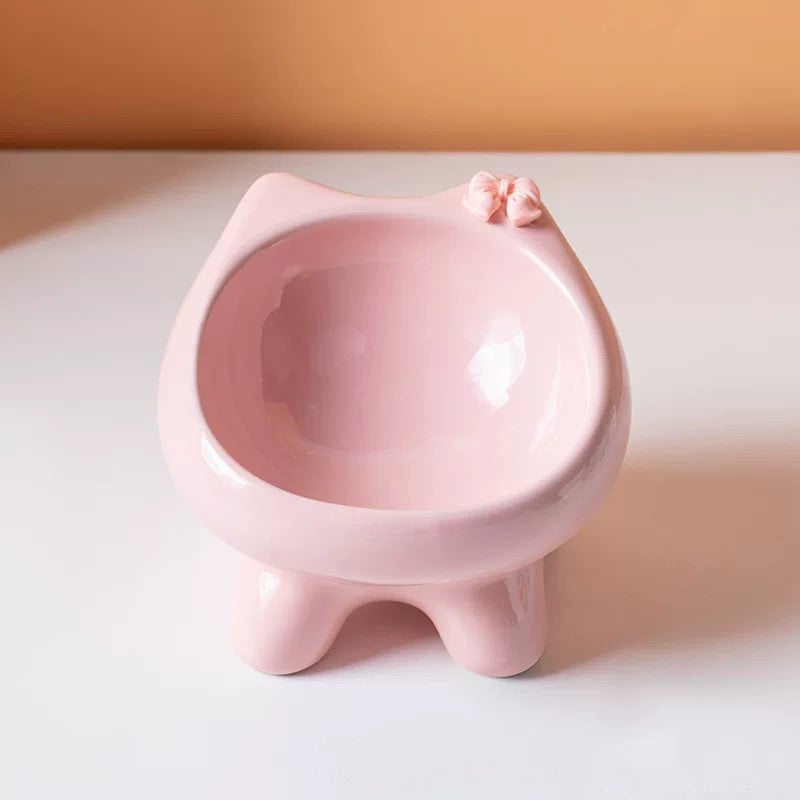 A front view of the premium pink cat-ear ceramic bowl, featuring an adorable 3D bow accent and four sturdy paw-shaped feet for spine protection.