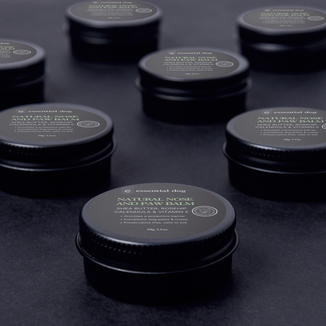 Artistic display of Essential Dog Paw Balm tins. Packaged in eco-friendly, plastic-free screw-top tins. The perfect &