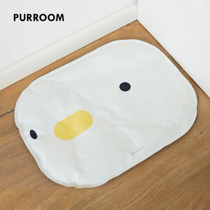 The PURROOM Chick Cooling Mat placed on a wooden floor, featuring an adorable and minimalist white chick face design with a yellow beak.