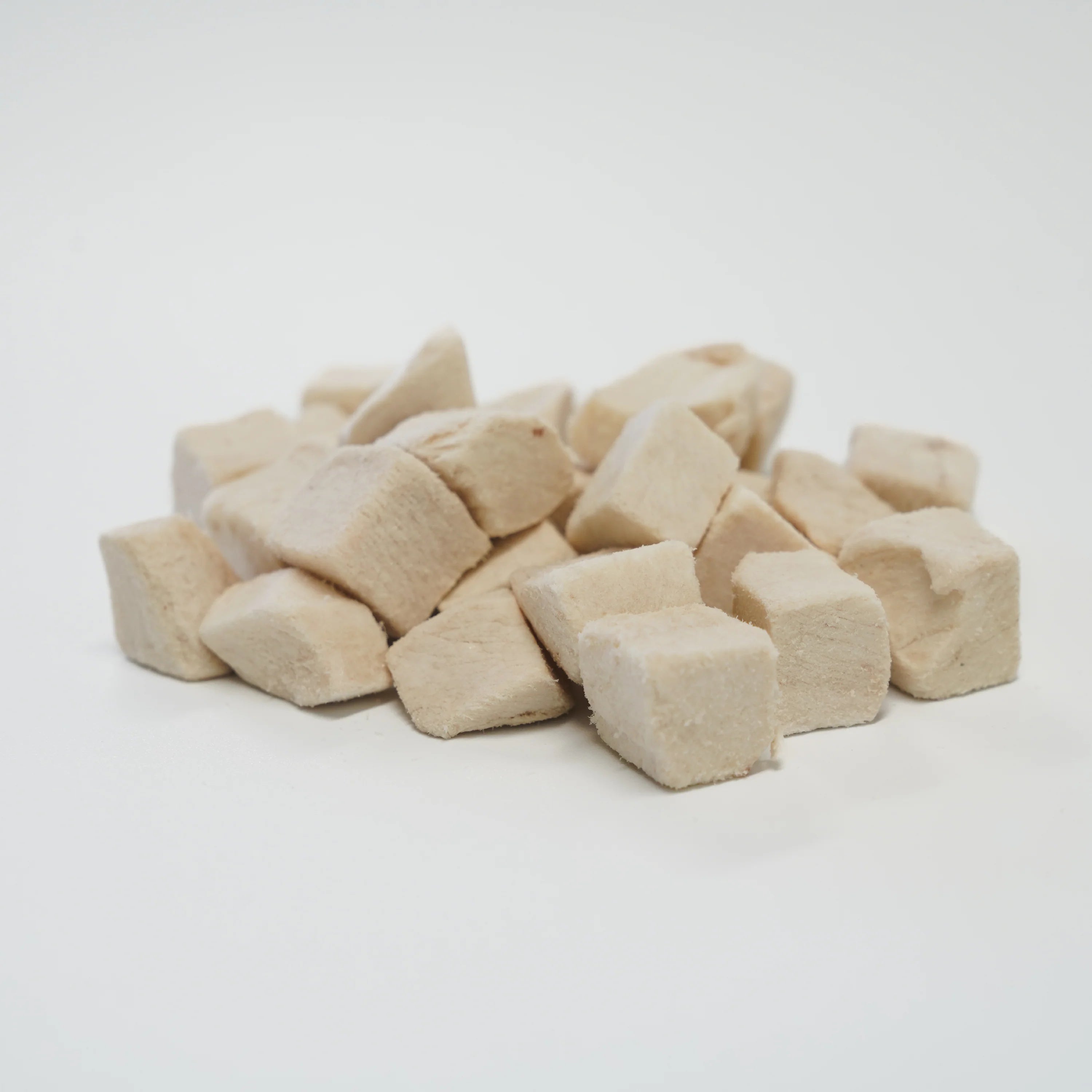 A close-up pile of RAFA raw freeze-dried Australian chicken breast cubes on a white background, highlighting the pure white meat texture of this ultra-lean, single-ingredient treat.