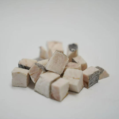 A close-up of RAFA raw freeze-dried New Zealand Hoki fillet cubes on a white background, highlighting the real fish skin and flaky white meat texture rich in natural Omega-3.