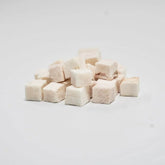 A close-up of RAFA raw freeze-dried New Zealand Pink Ling cubes on a white background, highlighting the pure, flaky white fish texture of this low-fat, high-protein seafood treat.
