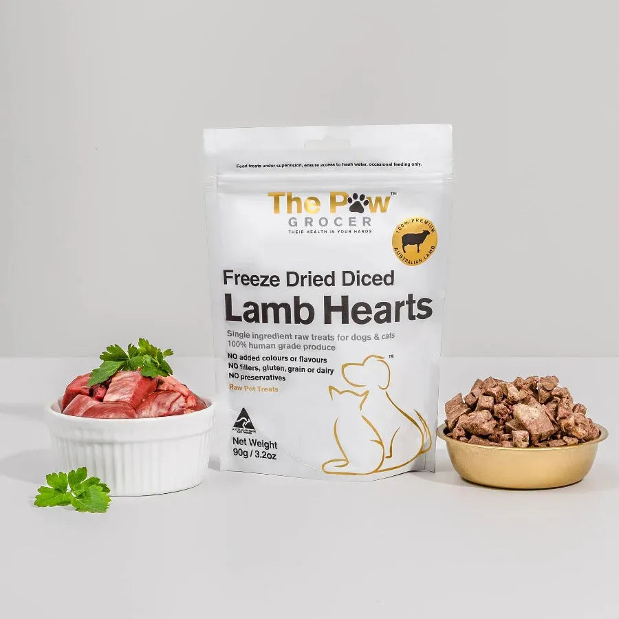 A bag of The Paw Grocer Lamb Hearts next to a bowl of raw fresh diced lamb hearts and a bowl of crunchy freeze-dried treats. A 100% single-ingredient raw treat for dogs and cats.