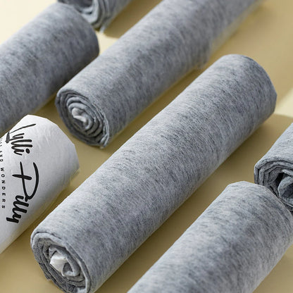 Close-up view of multiple rolled-up grey LYLLI PILLY pet pads, showcasing the skin-friendly membrane and printed logo on the waterproof backing.