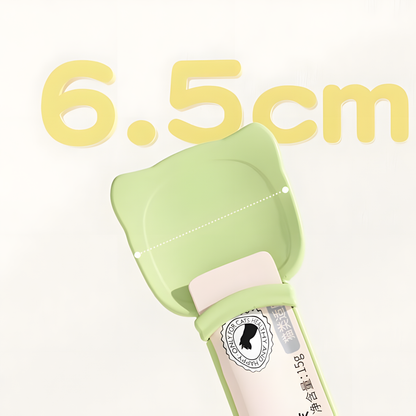 Close-up of the pastel green cat treat spoon featuring a wide 6.5cm cat-eared bowl. Designed to act as a protective barrier against sharp plastic wrappers.