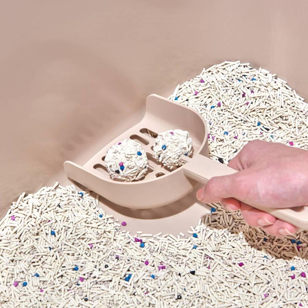 A close-up of a hand easily scooping two perfect, rock-solid clumps of Michu mixed tofu cat litter, showing absolutely no sticking to the bottom of the box and a mess-free clean-up experience.