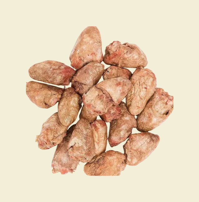 A close-up view of premium freeze-dried chicken heart pet treats on a yellow background, showcasing the natural, unprocessed texture that provides a nutrient-dense reward for cats and dogs.