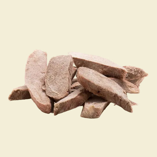 A close-up view of hypoallergenic freeze-dried duck breast tenders piled on a white background, highlighting the satisfying thick-cut texture and 70 percent pure protein content.